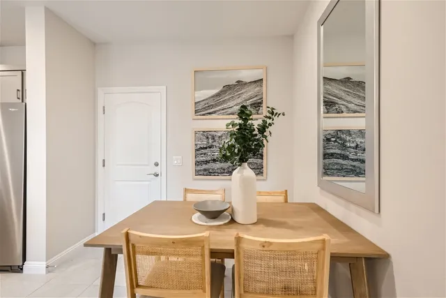 A dining room table with chairs and a vase with a plant on it.